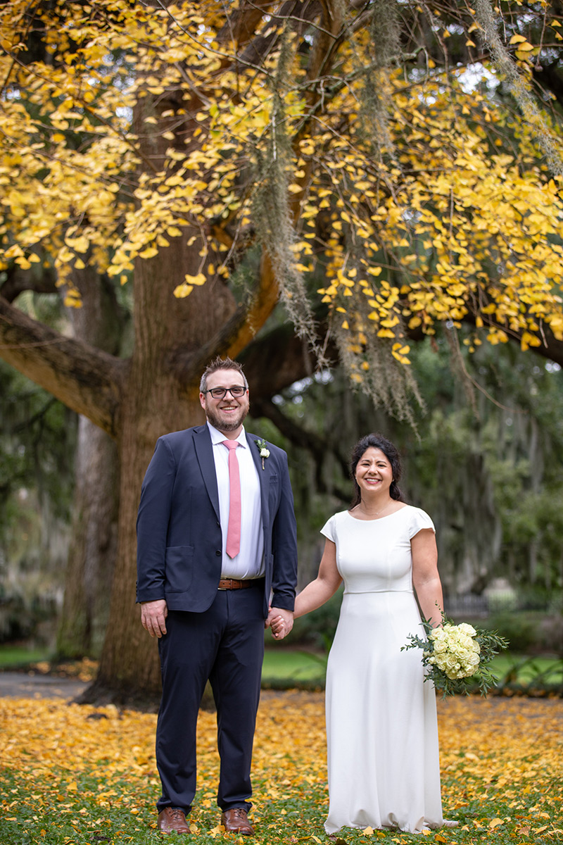 Happy couple with yellow leaves on a tree in Forsyth Park after their elopement.